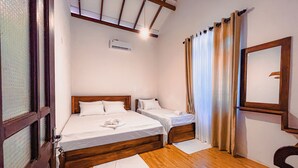 A hotel room with two beds, wooden flooring, a ceiling fan, and a window with curtains. - Dadas Villa - A Private Villa in Kandy & Peaceful Escape for Families & Couples (Kundasale, Sri Lanka)