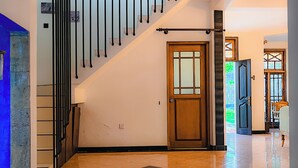 A modern interior with a staircase, a wooden door, and a view of the outdoors. - Dadas Villa - A Private Villa in Kandy & Peaceful Escape for Families & Couples (Kundasale, Sri Lanka)
