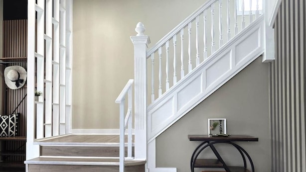 A staircase with white railings and wooden steps, a small table with a picture frame, and a wall with vertical blinds. - “Life is Good” | Accessible Stay Near the Falls (Niagara Falls)