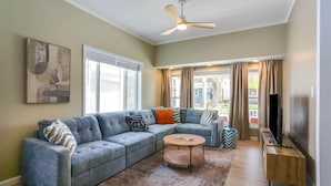 A living room with a sectional sofa, a coffee table, a TV stand, and a ceiling fan. - “Life is Good” | Accessible Stay Near the Falls (Niagara Falls)
