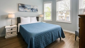 A bedroom with a bed, nightstands, a painting, and windows. - “Life is Good” | Accessible Stay Near the Falls (Niagara Falls)
