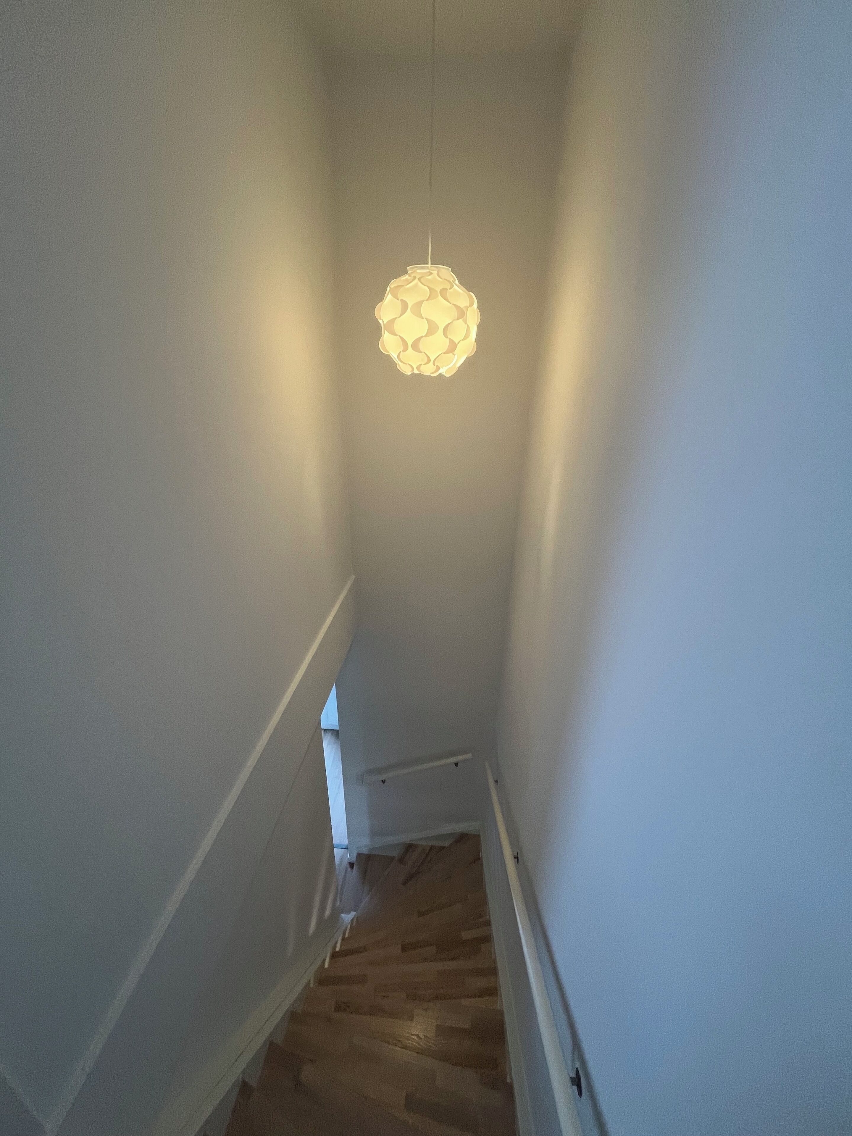 A narrow staircase with wooden steps and white walls.