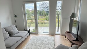 Un soggiorno moderno con un divano grigio, un tappeto bianco e un televisore su un mobile in legno.