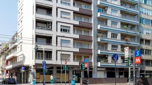 A multi-story building with balconies, a pedestrian crossing, and traffic signs.