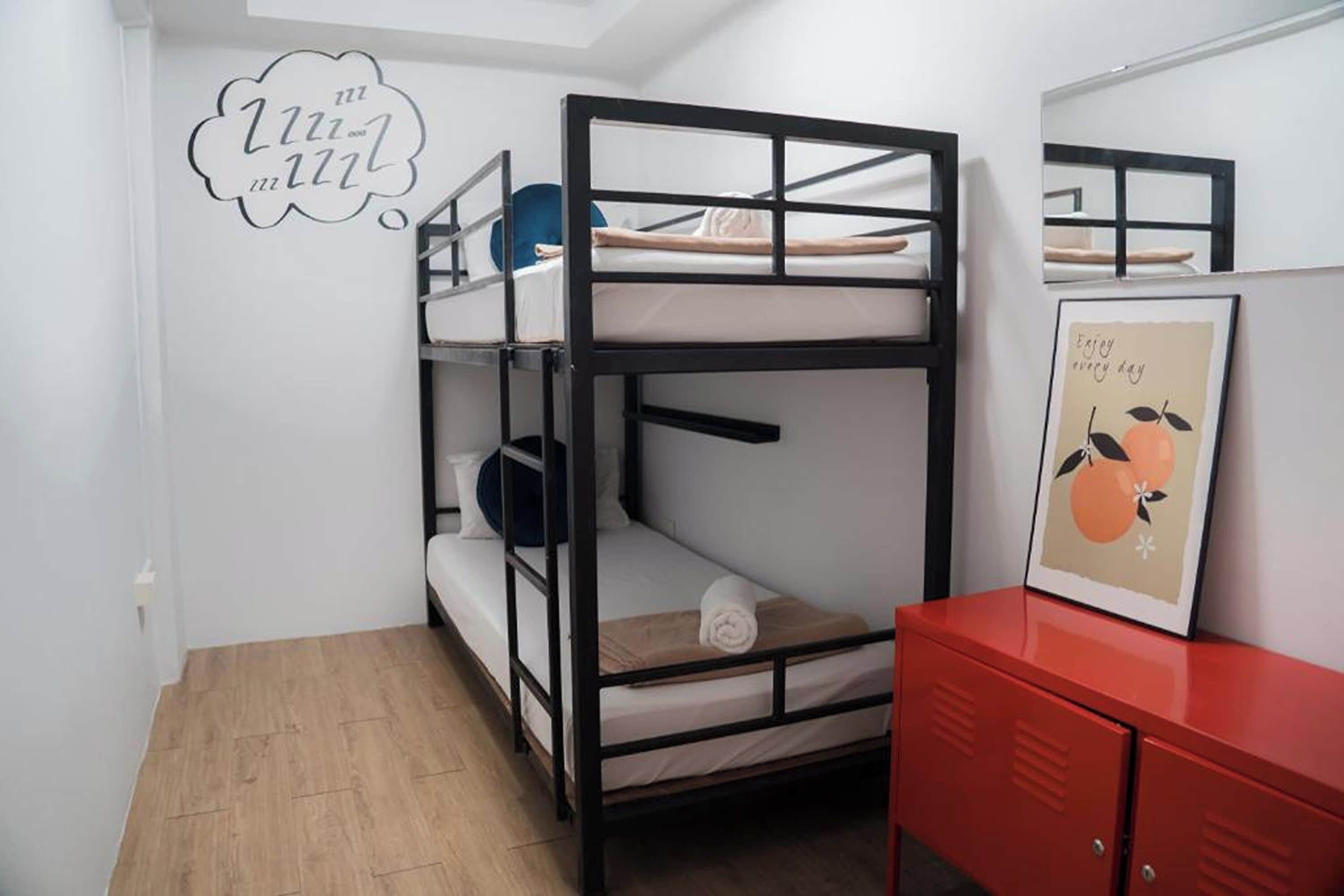 A bunk bed room with a red cabinet and a framed picture on the wall.