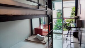 Una habitación pequeña con una cama litera, una mesita y una silla.