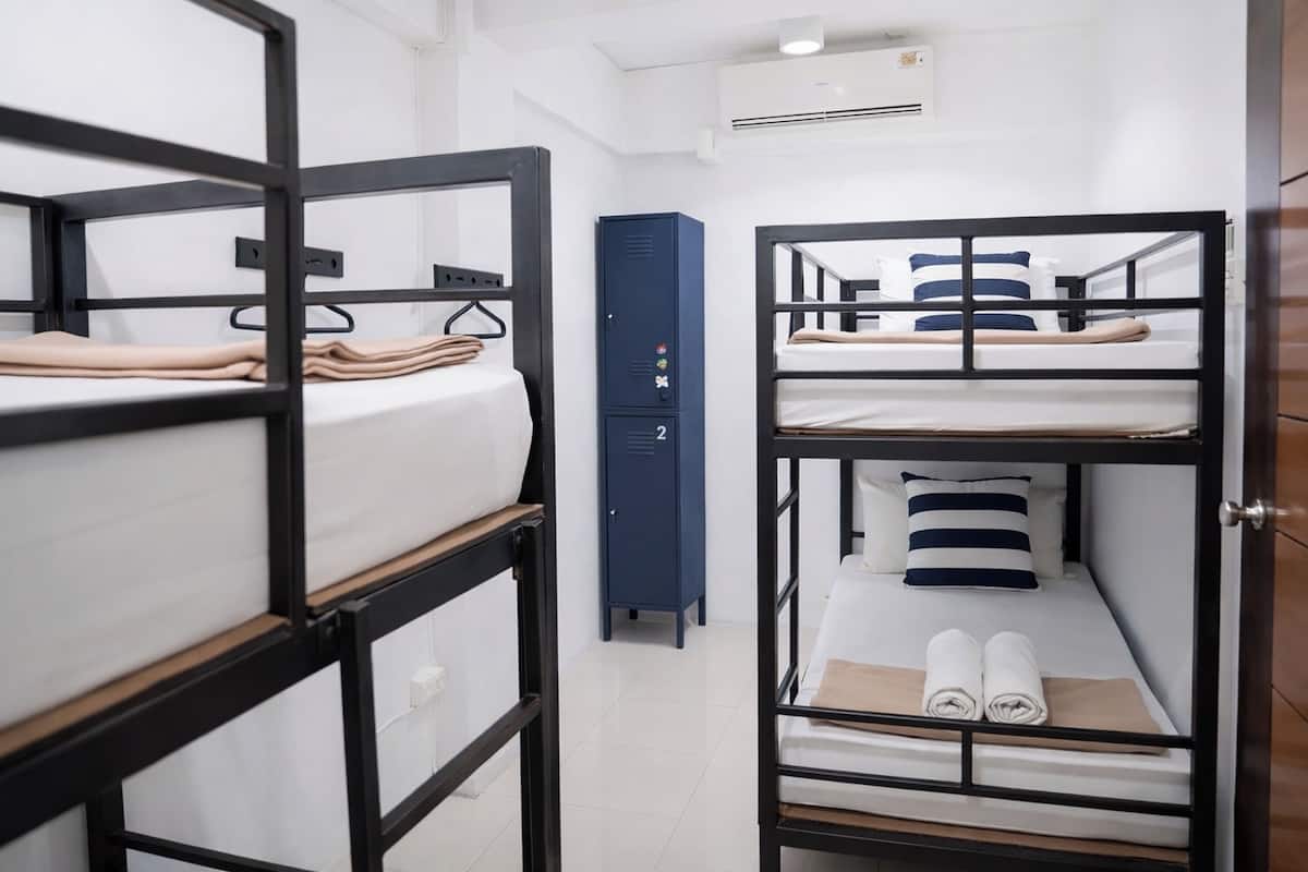 A dormitory room with bunk beds, a blue storage unit, and a white wall.