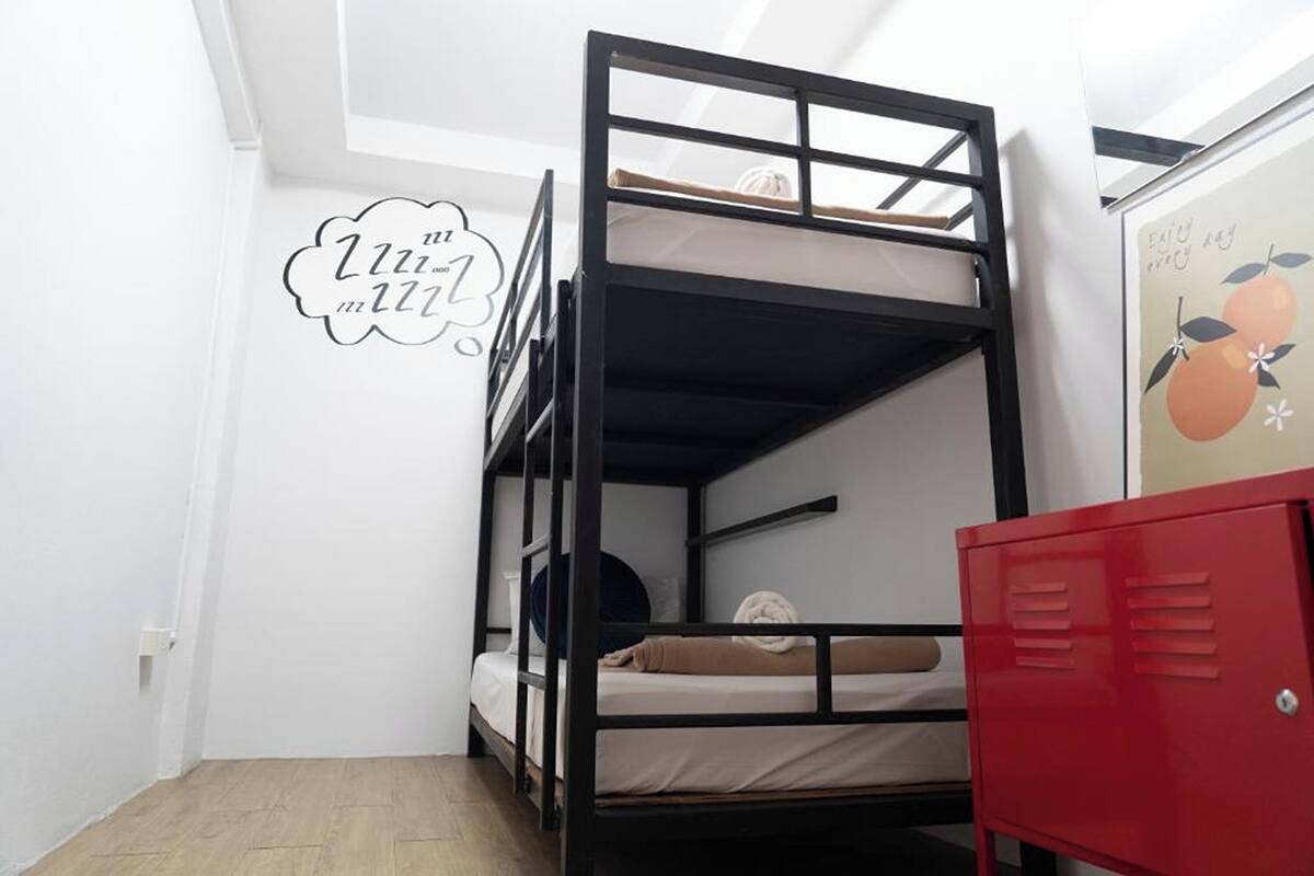 A bunk bed room with a red locker, white walls, and a ceiling light.