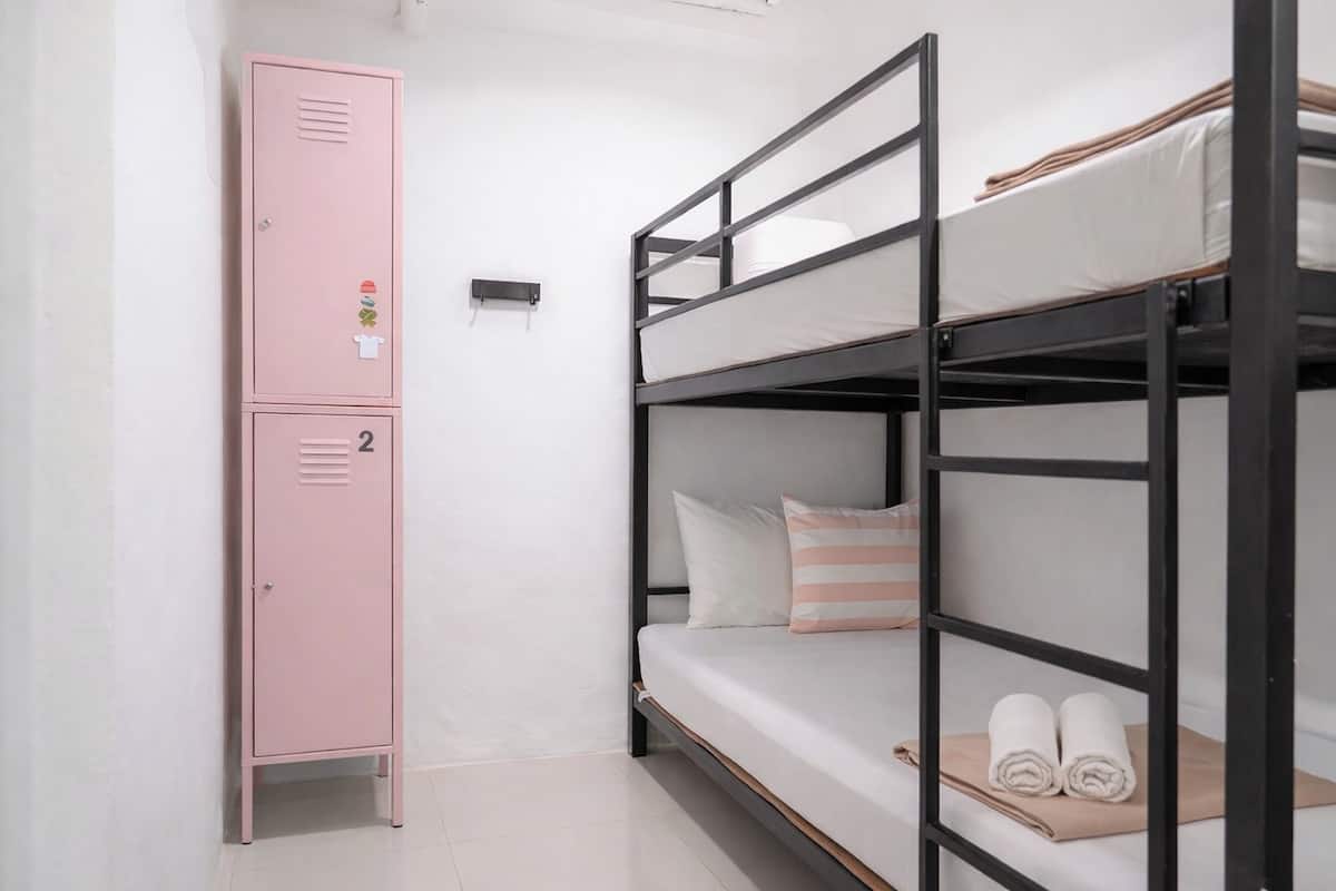 A bunk bed with a pink locker and a small shelf.