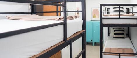 A dormitory room with bunk beds, a teal cabinet, and a framed picture on the wall.