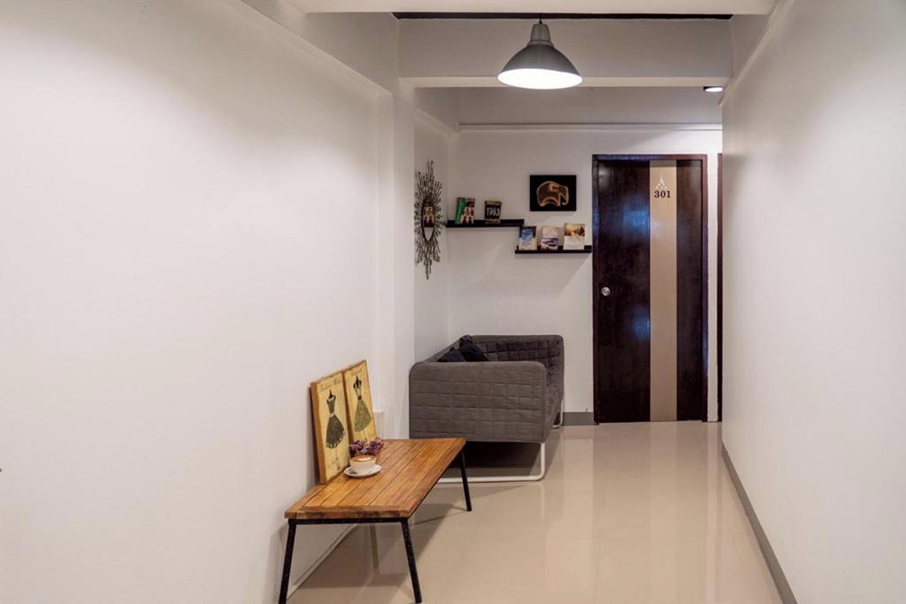 A hallway with a wooden table, a grey sofa, and a door marked with the number 301.