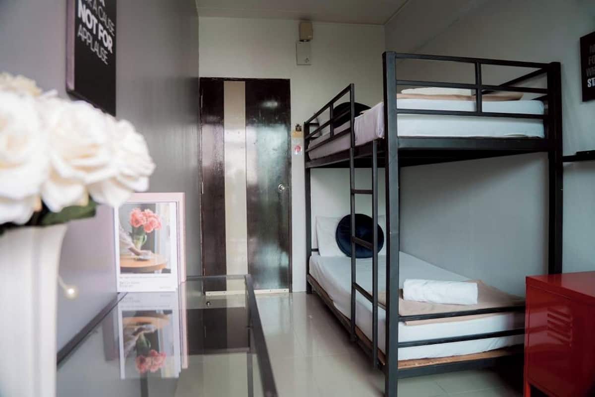 A bunk bed room with a glass door, a red dresser, and a framed picture on the wall.