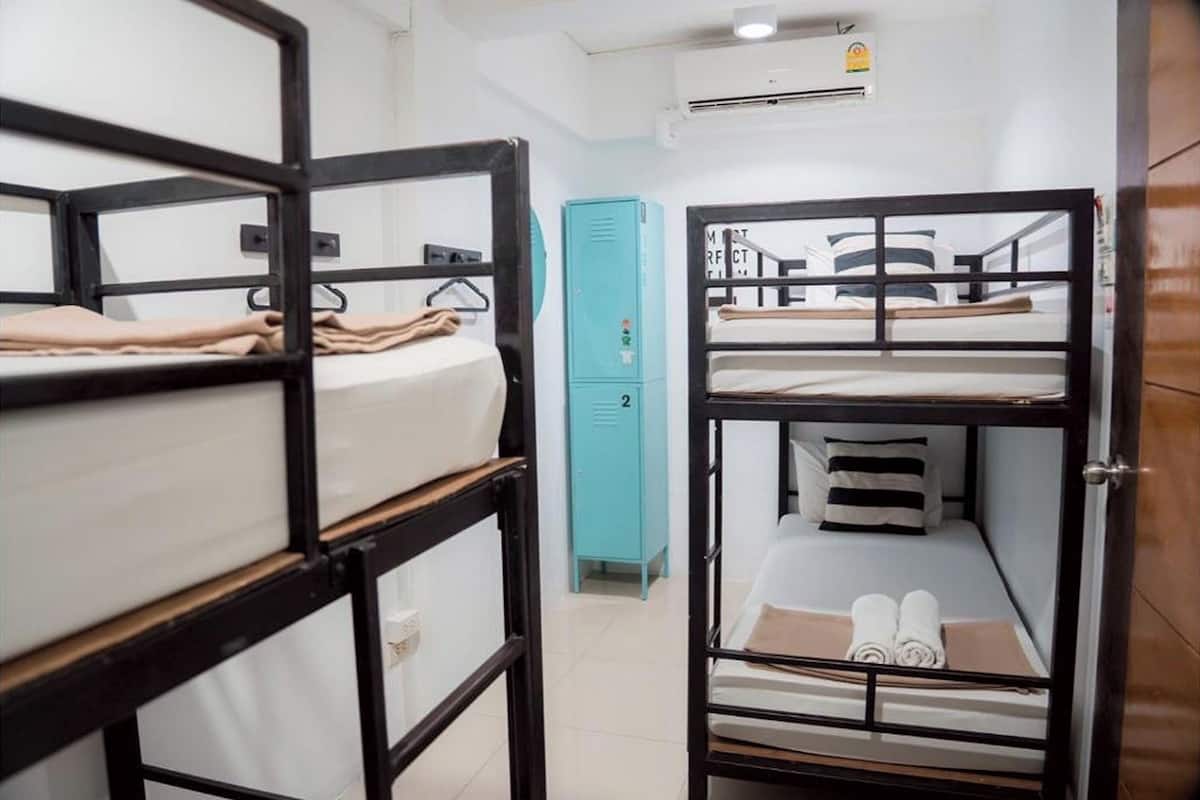 A dormitory room with bunk beds, a teal-colored storage unit, and a white door.