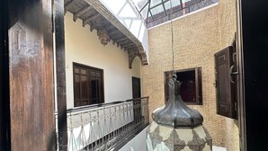 A traditional courtyard with a hanging lantern, a wooden door, and a view of the sky through a glass ceiling. - Riad 3 rooms 306m2 500 m from Place Jemaa el-Fna (Marrakech)