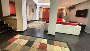 A spacious living area with a staircase, a red sofa, and a flat-screen TV mounted on the wall. - Riad 3 rooms 306m2 500 m from Place Jemaa el-Fna (Marrakech)