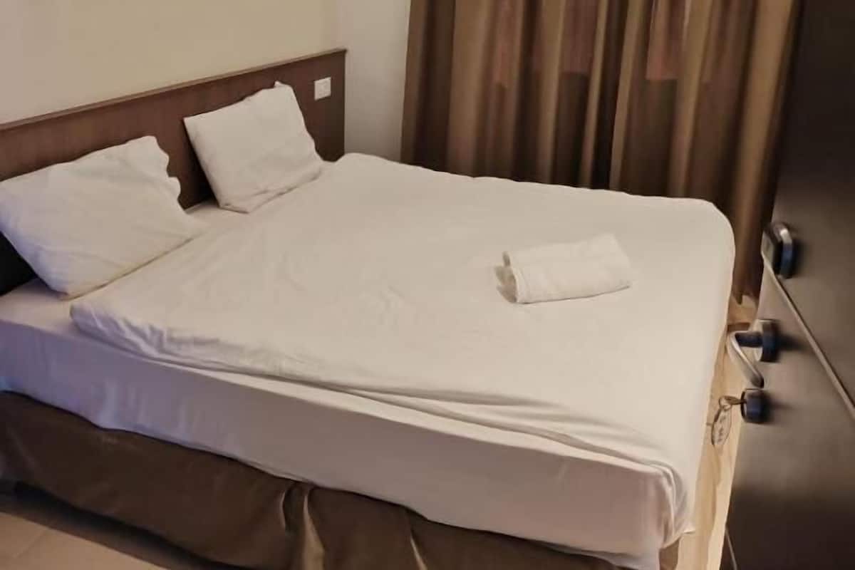 A hotel room with a bed, a headboard, a nightstand, and a curtain.
