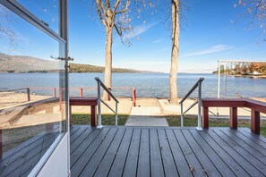 A wooden deck with a glass railing overlooking a lake, trees, and distant hills. - Four Seasons cottage on Lake Champlain waterfront (WIllsboro)