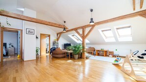 A spacious loft with high ceilings, exposed wooden beams, and skylights. - Bright and airy apartment in unique suburb (Praha 3)