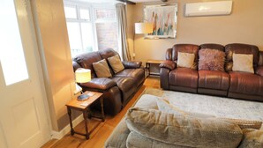 A living room with two leather sofas, a wooden coffee table, a lamp, and a painting on the wall.