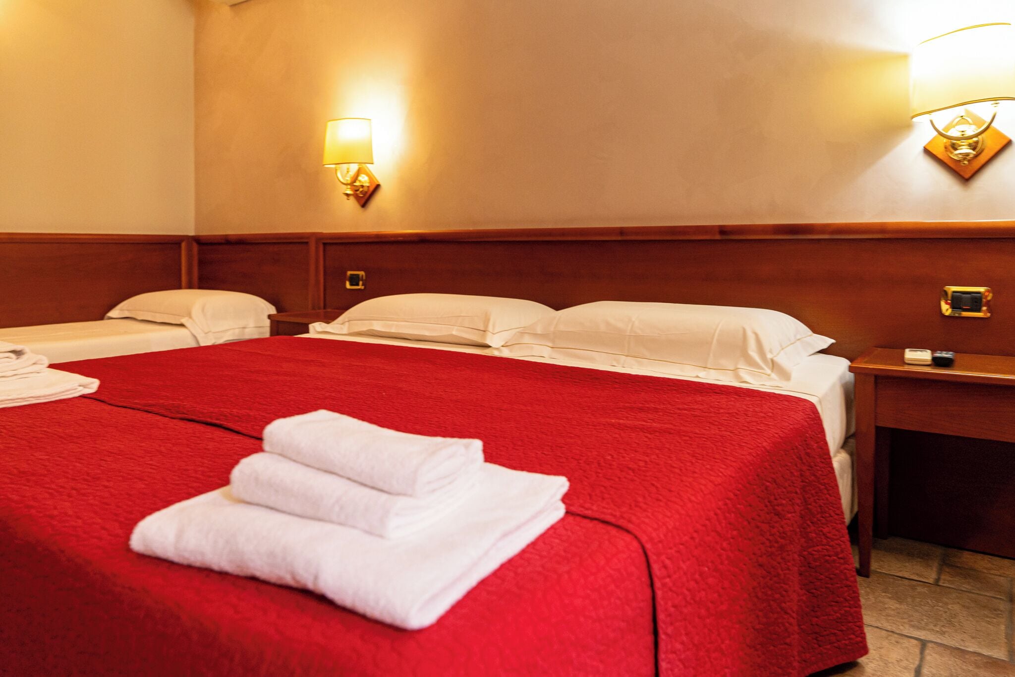 Ein Hotelzimmer mit einem großen Bett, zwei Nachttischen und zwei Wandlampen.
