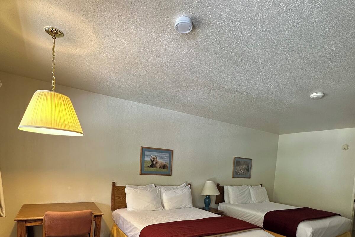 A hotel room with two beds, a desk, and a chair.
