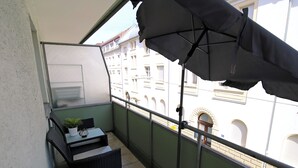 En balkon med et bord, stol og en potteplante.