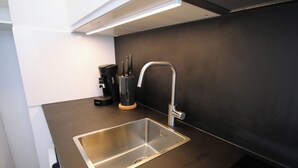 Et moderne køkken med en stålvask, kaffemaskine og et knivblok.