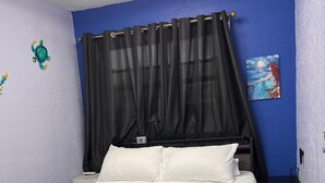 Un dormitorio con cama, cortinas negras, una mesita de noche, un reloj de pared y un cuadro.