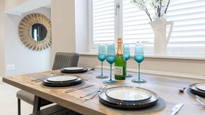 A dining table set with plates, cutlery, and blue glasses, with a bottle of champagne in the center. - Tŷ Haul (Sun House) is not your typical holiday let. (Cefn-mawr)