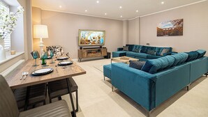 A modern living room with a blue sofa, a wooden coffee table, and a TV on a wooden stand. - Tŷ Haul (Sun House) is not your typical holiday let. (Cefn-mawr)