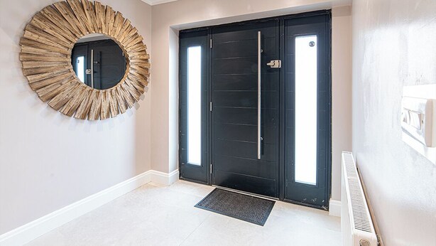 A modern entrance with a black door, a circular mirror, and a tiled floor. - Tŷ Haul (Sun House) is not your typical holiday let. (Cefn-mawr)