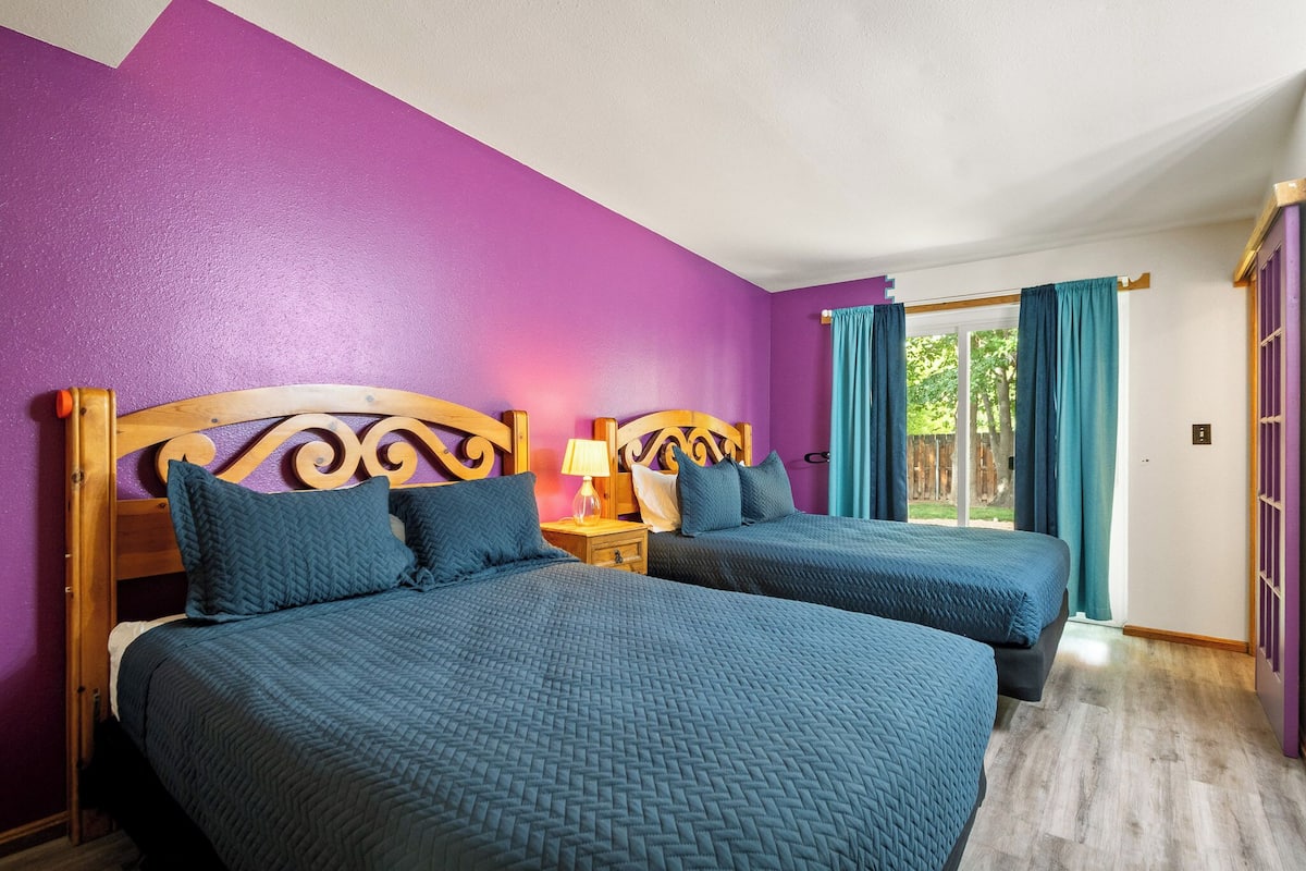 A room with two beds, purple walls, and a wooden headboard.