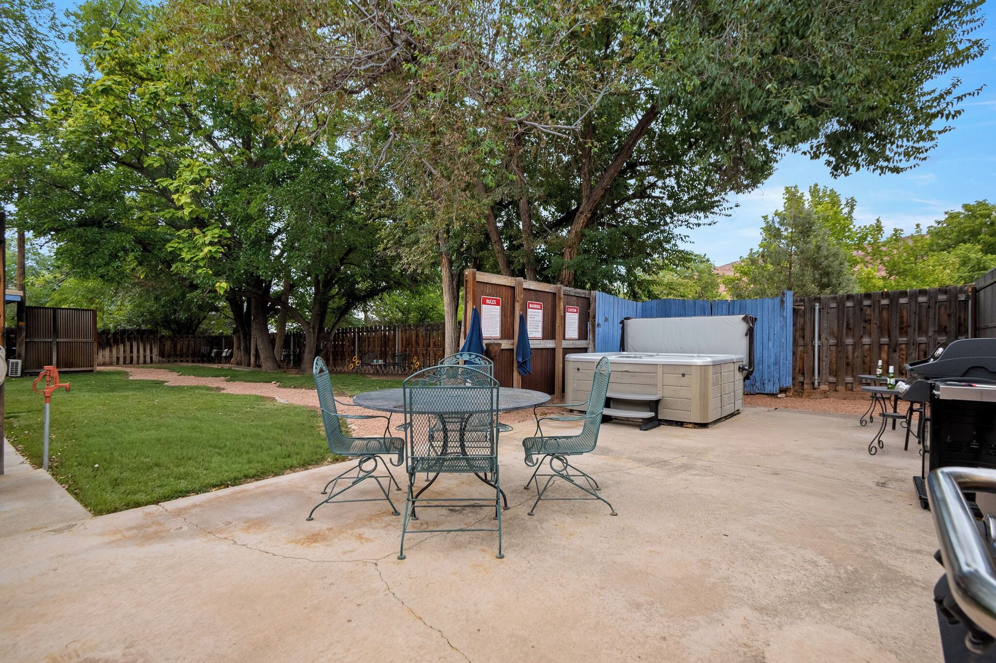 A backyard with a metal table and chairs, a barbecue grill, and a shed.