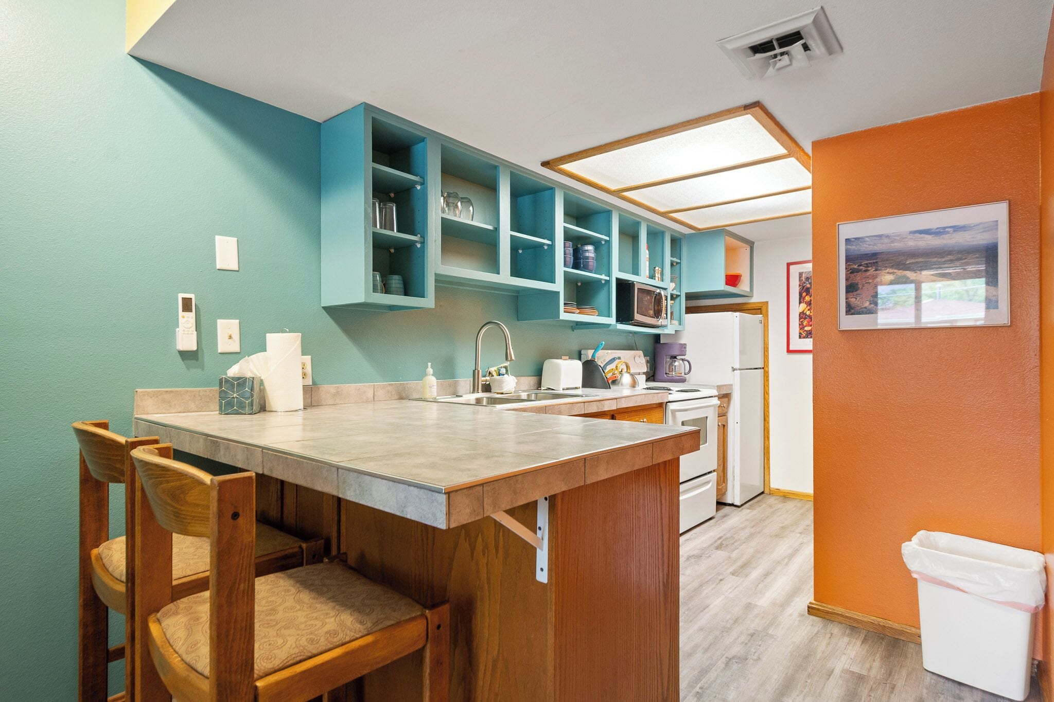 A kitchen with teal cabinets, a wooden dining table, and chairs.
