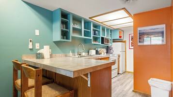 A kitchen with teal cabinets, a wooden dining table, and chairs.
