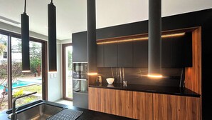 Een moderne keuken met een zwart aanrecht, houten kastjes en hanglampen.