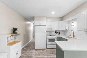 A modern kitchen with white cabinets, a built-in oven, a microwave, and a sink with a gold faucet. - Quaint Rennovated 2-Bedroom close to the solar farms and Honda (Raymond)