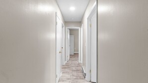 A hallway with white walls, a light-colored floor, and doors on both sides.