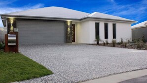 A modern two-story house with a garage, a gravel driveway, and a well-maintained lawn. - Azure on Bondi Place (Kingscliff)