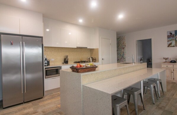 A modern kitchen with a central island, stainless steel appliances, and a tiled backsplash.