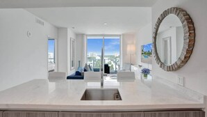 A modern kitchen with a large island, a view of the city, and a unique decorative mirror. - Fort Lauderdale Luxe - Beach + Rooftop Pools (Fort Lauderdale)