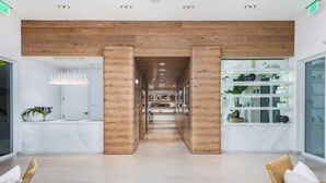 A modern hotel lobby with a central wooden column, a reception desk, and a plant display. - Fort Lauderdale Luxe - Beach + Rooftop Pools (Fort Lauderdale)