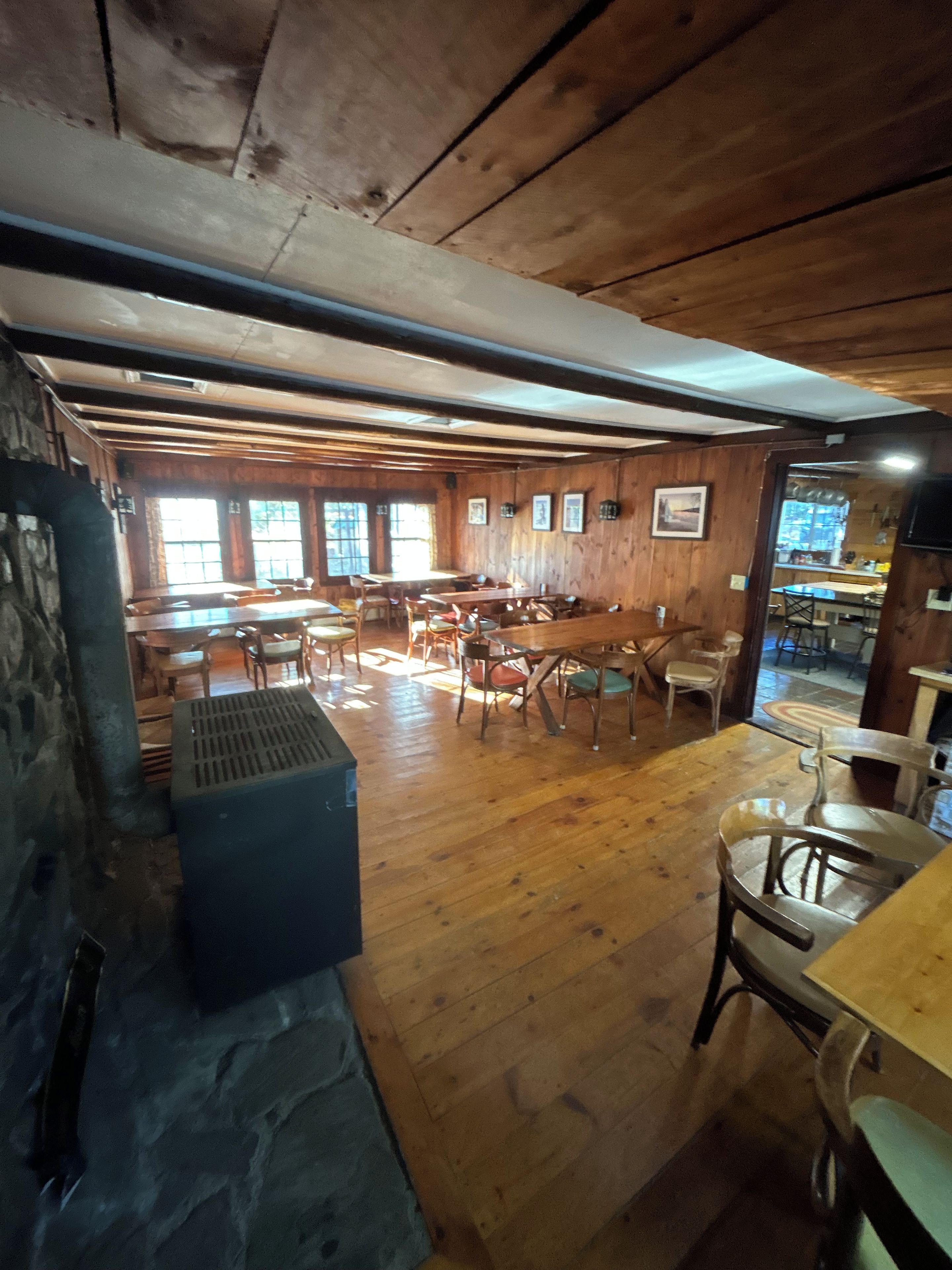 A wooden interior with a bar area, seating, and a stone wall.