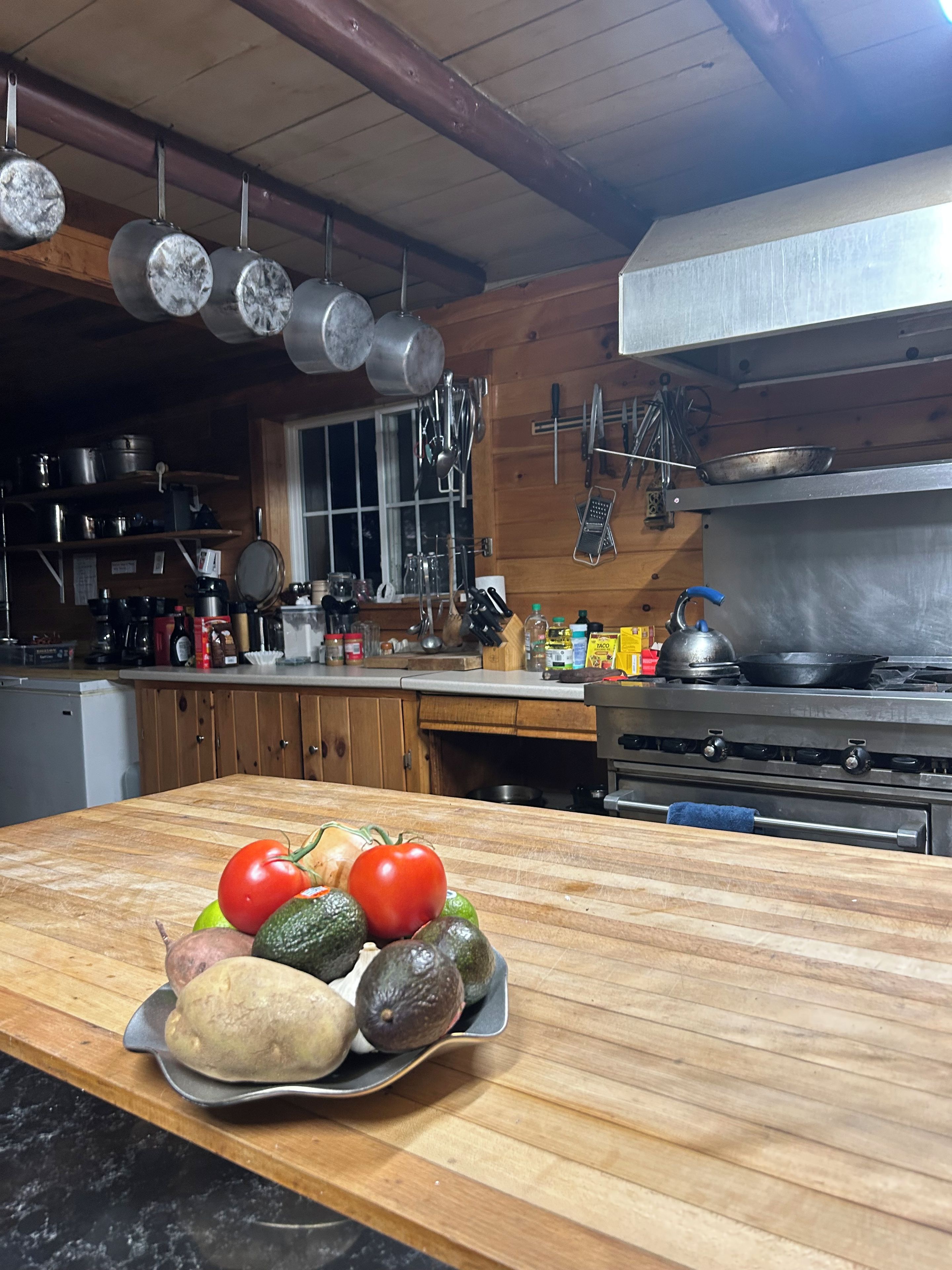 A kitchen with wooden cabinets, a stove, and hanging pots.