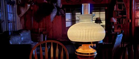 A wooden table with a lamp in a dimly lit room with wooden walls and a ceiling with exposed beams.