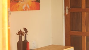 A room with a wooden desk, two vases, and a painting of a savannah scene. - Sibebe Hills Vista (Mbabane)