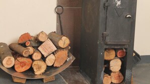 A wood-burning stove with logs stored nearby. - Sibebe Hills Vista (Mbabane)