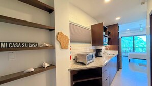A modern kitchen with a built-in toaster, a coffee maker, and a wooden wall decor. - Hibisco Belize (San Pedro)