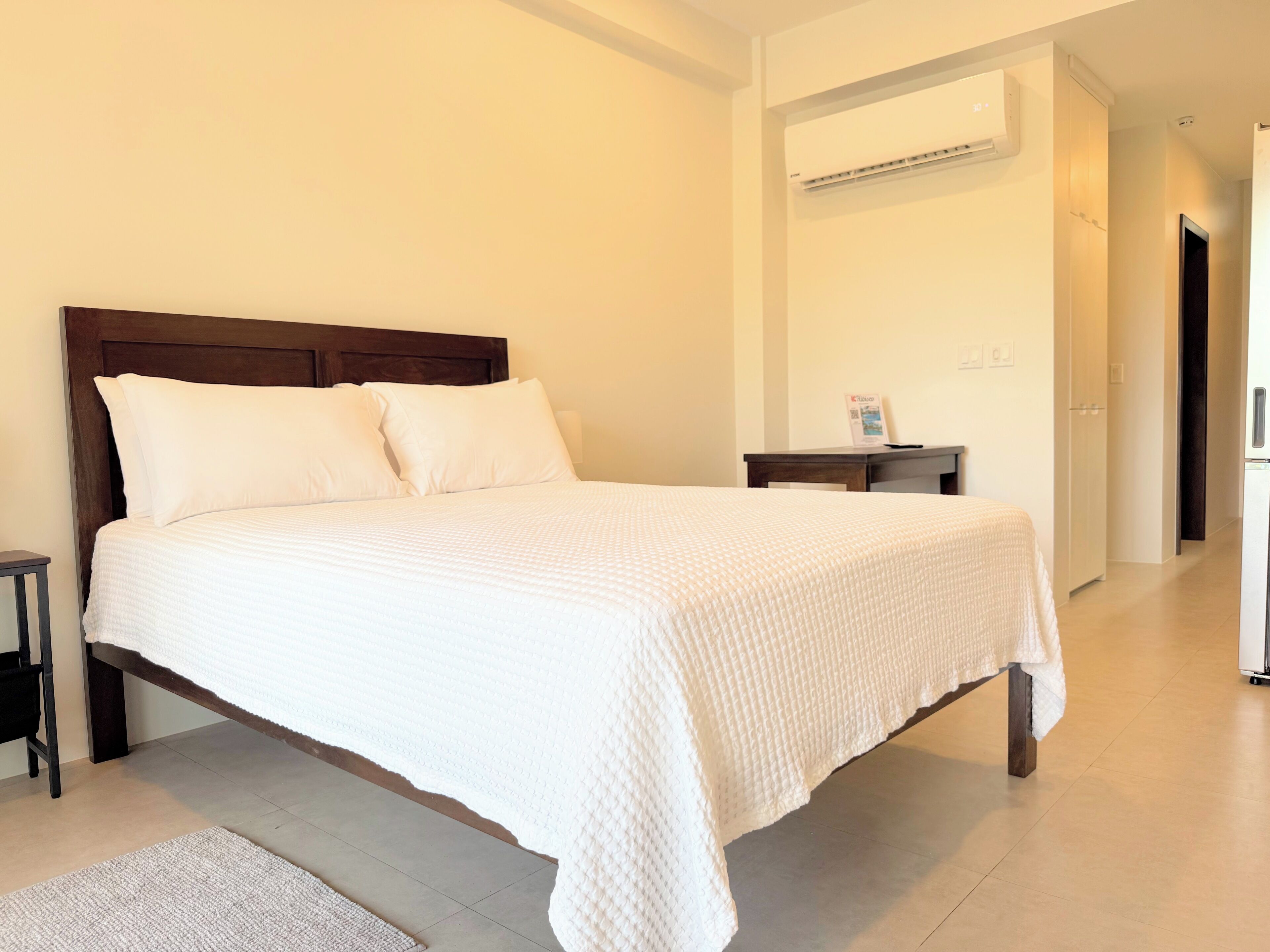 A neatly made bed with white bedding in a hotel room.