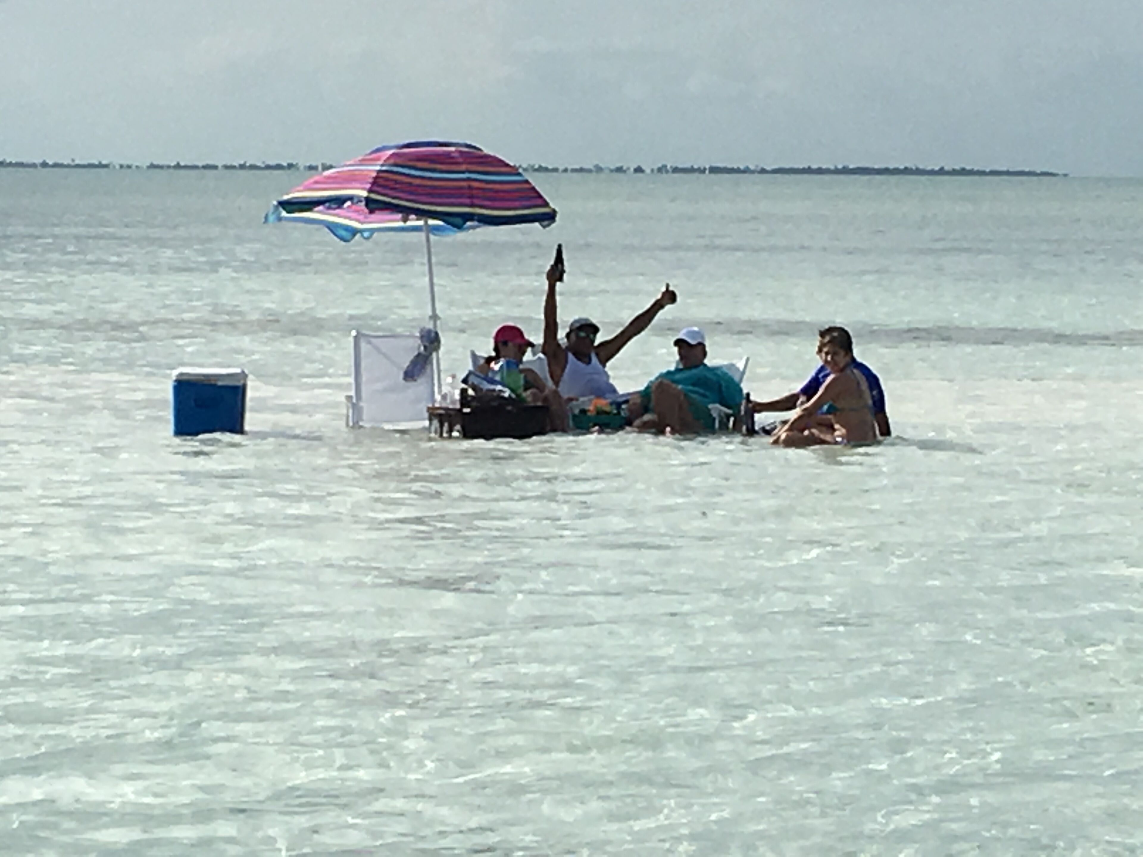 A group of people in a boat on a body of water with an umbrella.